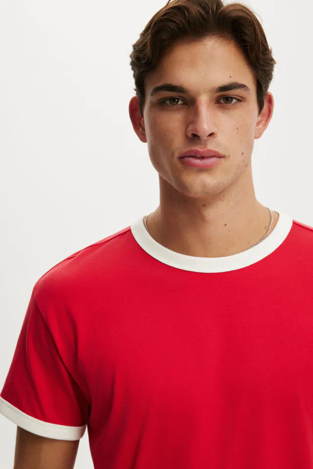 Man wearing red and white crew neck t-shirt against white background