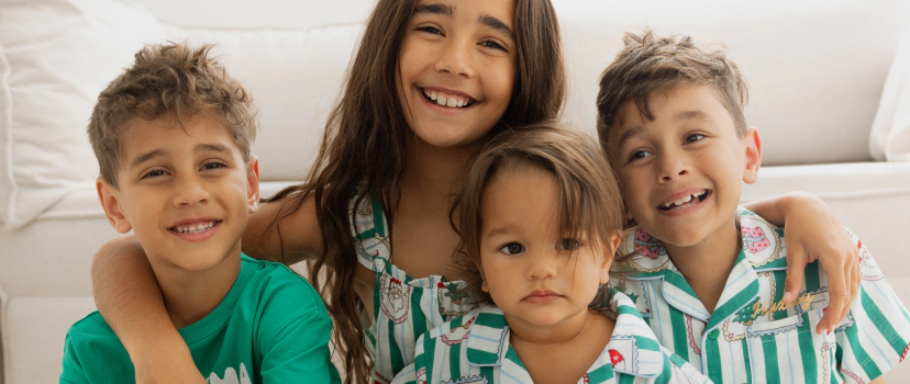 Four smiling children wearing green and white Cotton On clothing posed together against a white background