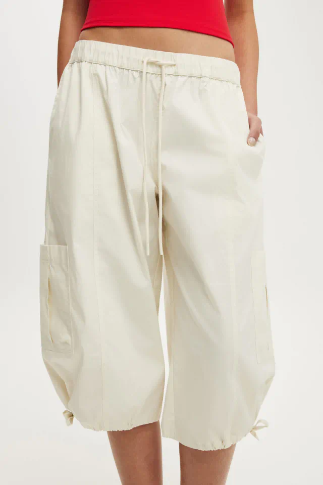 Woman wearing red crop top and cream cargo capri pants with drawstring waist and side pockets