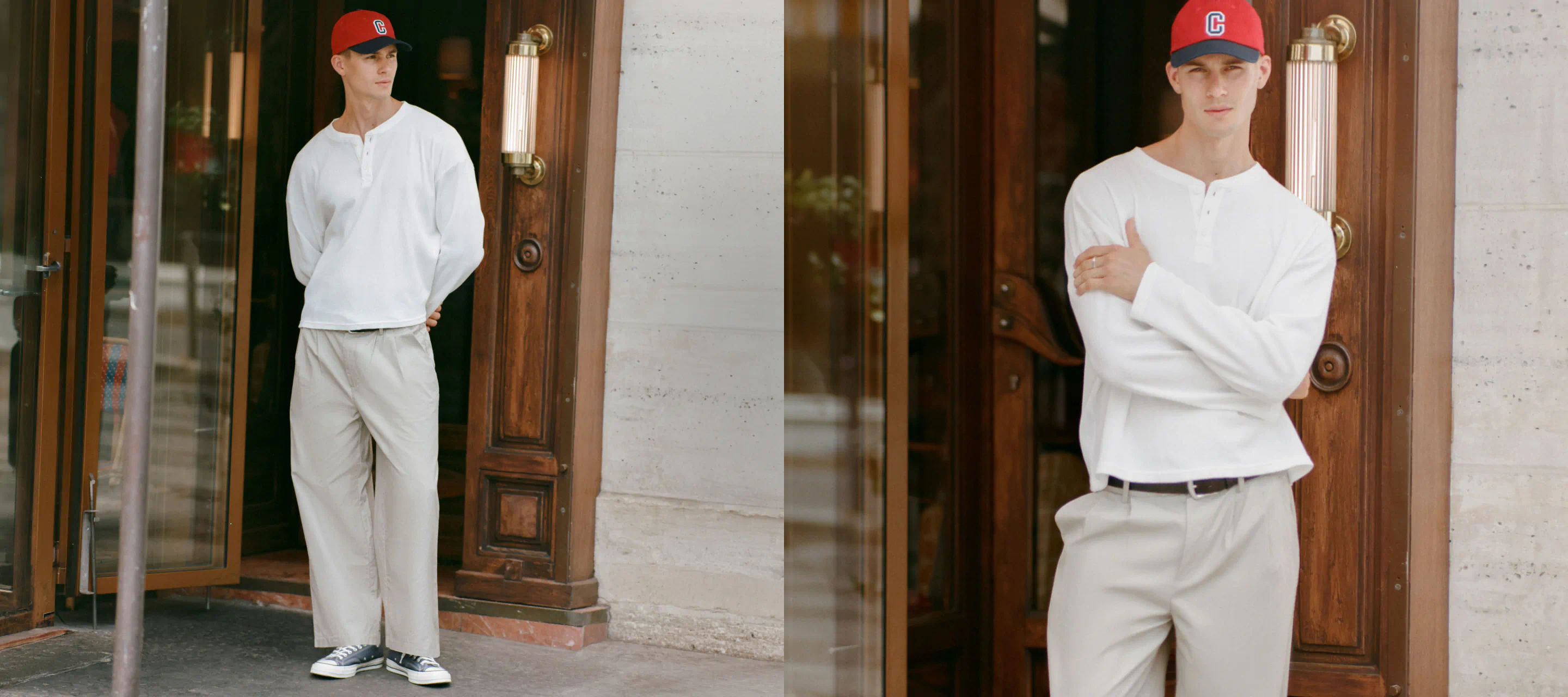 Two men wearing white long-sleeve shirts, cream pants, and red baseball caps pose against wooden doorways in an urban setting
