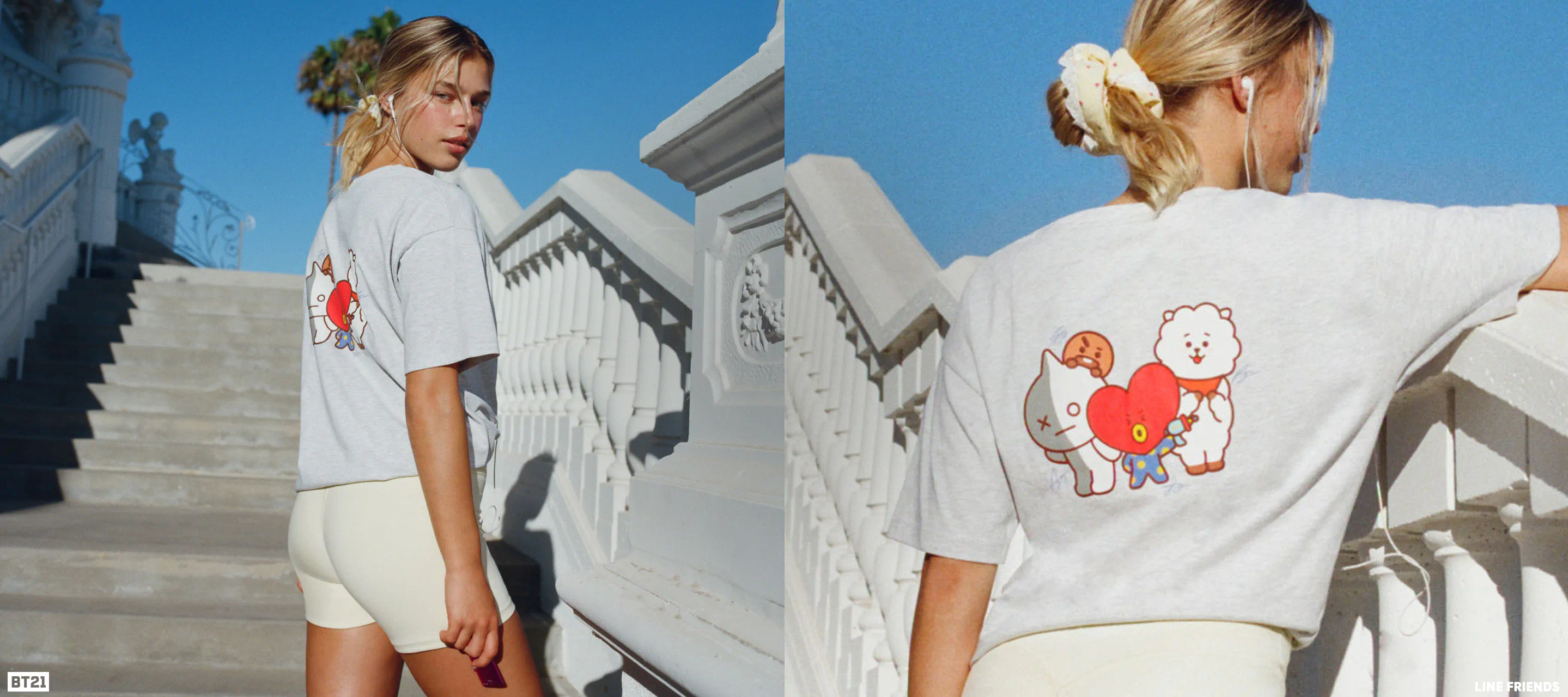 Two models wearing white graphic t-shirts with cute character designs, styled with cream shorts against a bright Mediterranean architectural background