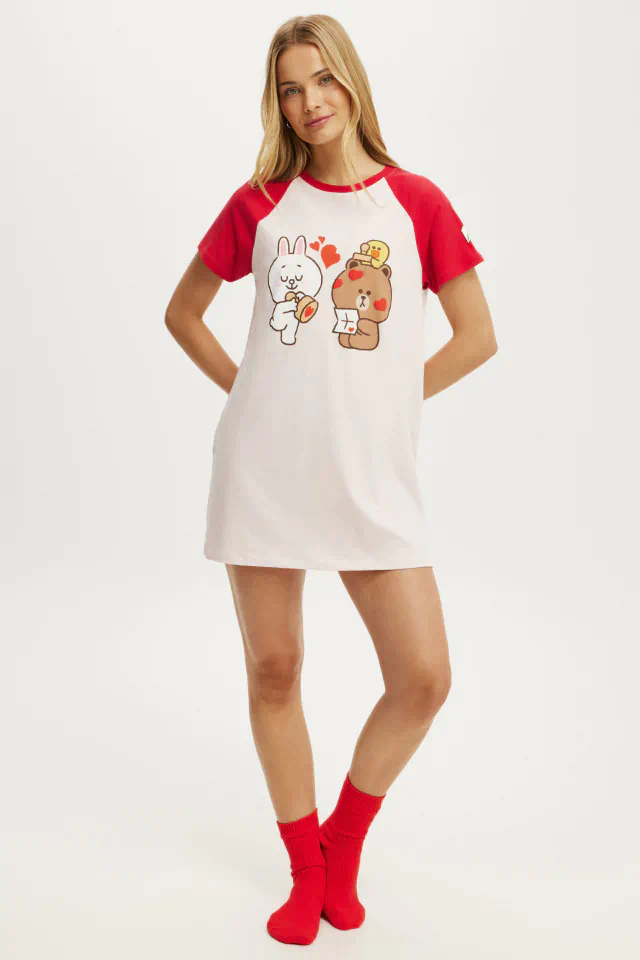 Woman wearing red and white raglan t-shirt dress with cute cartoon characters and red socks, standing against white background