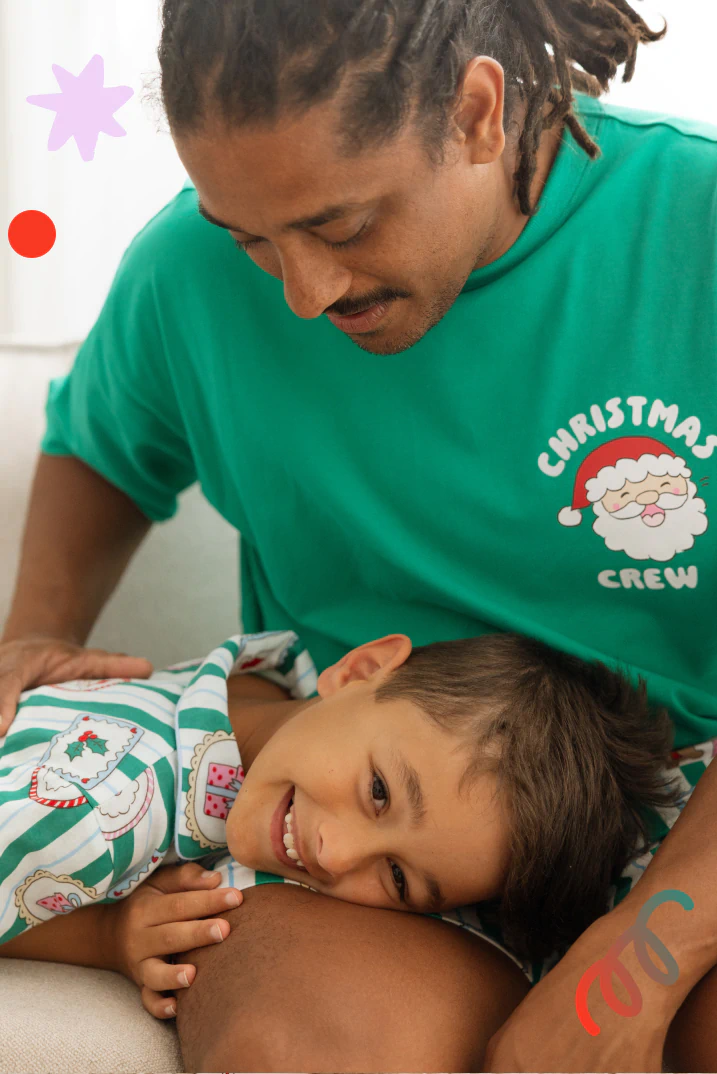 Adult and child wearing matching green "Christmas Crew" Santa t-shirts with festive holiday prints, smiling together