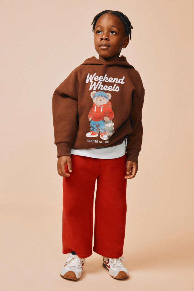 Back view of child wearing light pink t-shirt with "Let's Play" text and animated puppy characters graphic, paired with pink pants